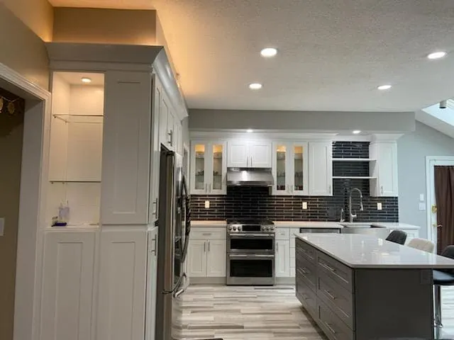 Open-plan white and gray kitchen with glass cabinets